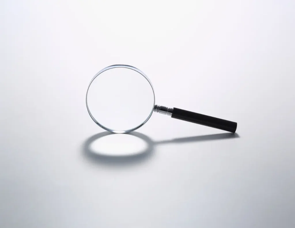 Magnifying glass resting on a white background with visible shadow.